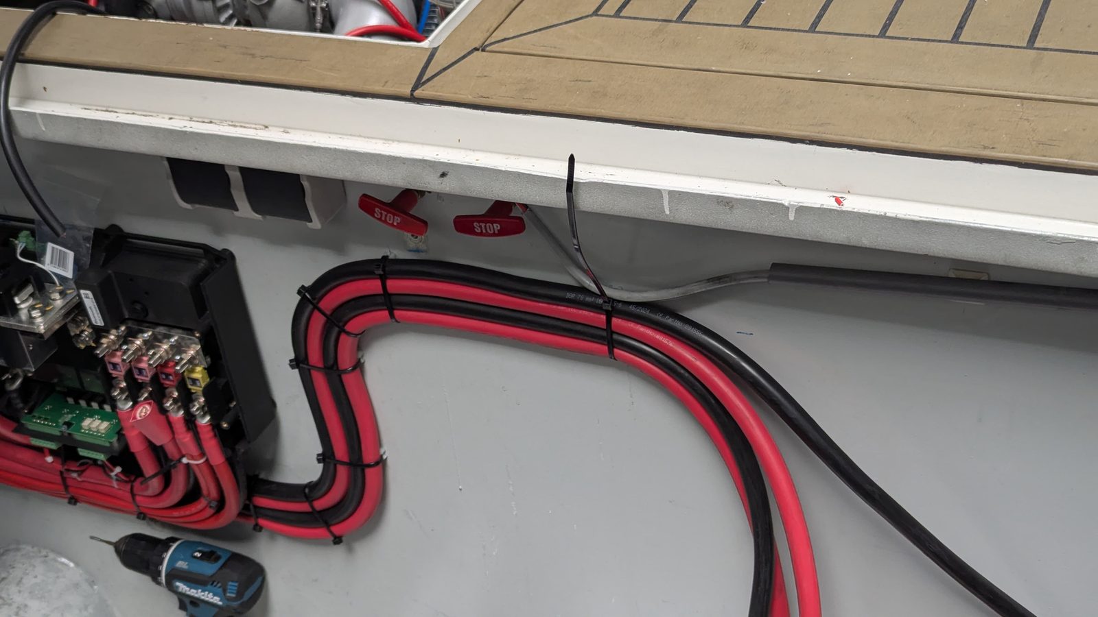 Strak gebundelde 70mm² accukabels in nette boog langs de wand — vakwerk in scheepselektrotechniek
